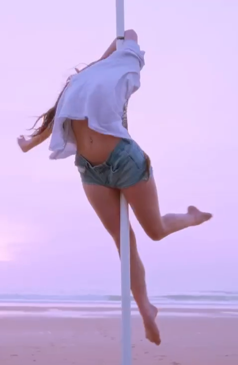 Image montrant une femme faire du poledance avec en fond une plage et l'océan